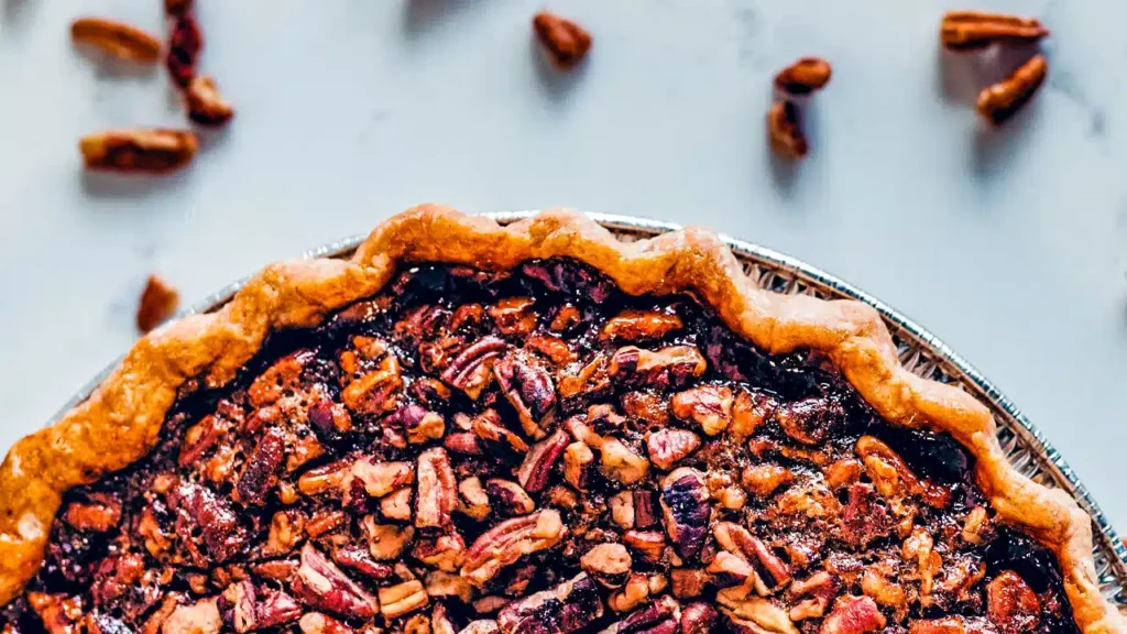 Tarta de calabaza recién horneada con una capa crujiente de nueces pecanas en la parte superior. Esta receta con nueces ofrece una combinación perfecta de sabores otoñales y texturas satisfactorias en cada bocado.