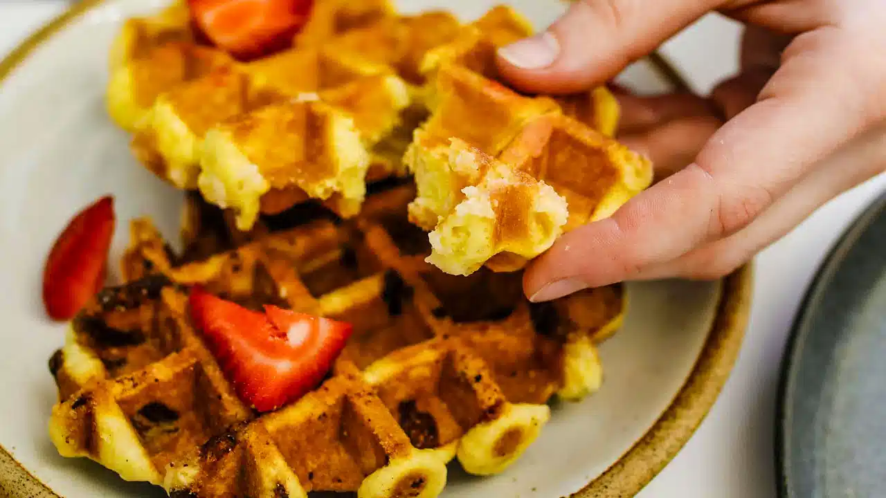 Waffles recién hechos cubiertos con jarabe de maple y nueces, una tentadora indulgencia para disfrutar en cualquier momento del día.